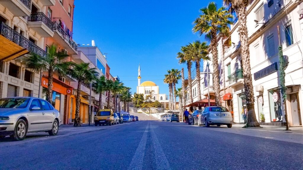 Main Shop Street in Durres: Mosque Silhouette, Palm Trees, and Bustling Activity