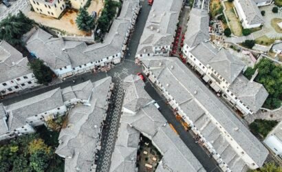 Aerial view of Gjirokaster's historic center showing closely packed gray stone buildings resembling a puzzle.