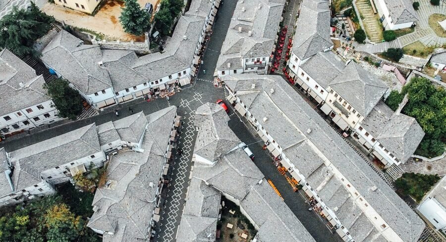 Aerial view of Gjirokaster's historic center showing closely packed gray stone buildings resembling a puzzle.