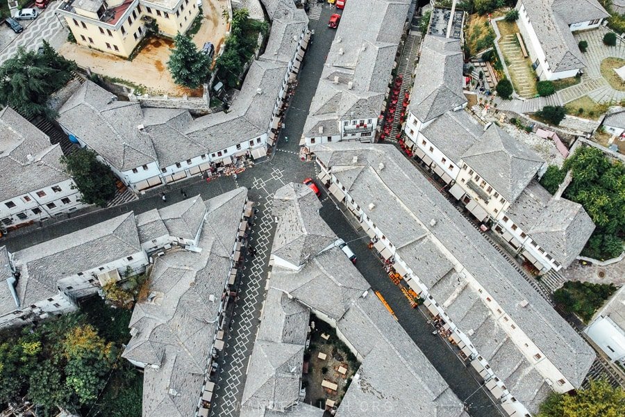 Aerial view of Gjirokaster's historic center showing closely packed gray stone buildings resembling a puzzle.