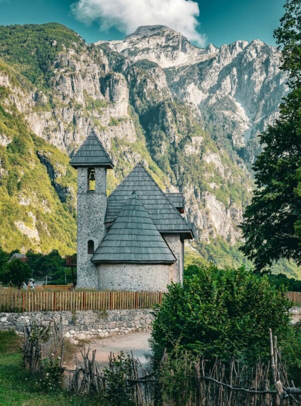 Historic Lock-in Tower (Kulla e Ngujimit) surrounded by a green valley and mountains in Theth, Albanian Alps