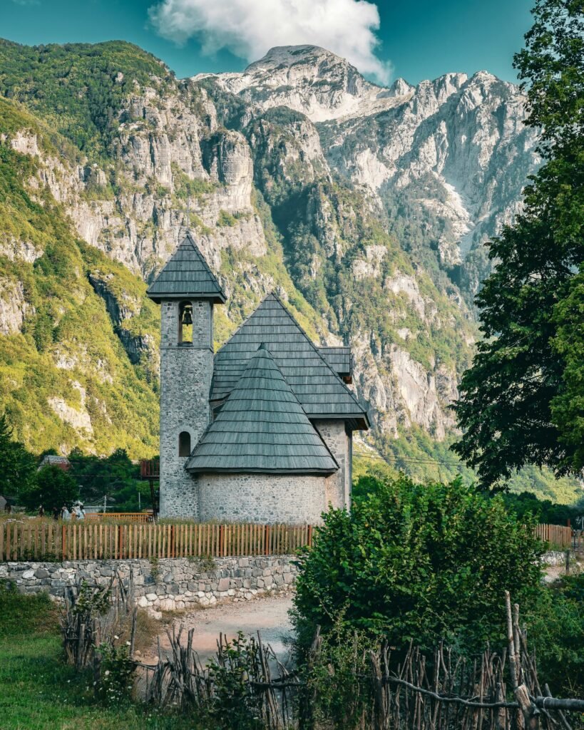 Historic Lock-in Tower (Kulla e Ngujimit) surrounded by a green valley and mountains in Theth, Albanian Alps